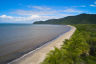 An aerial shot of a long stretch of beach where the rainforest meets the reef on Dabu Jajikal Country.