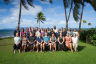 Group photo of workshop participants in front of palm trees and the ocean.
